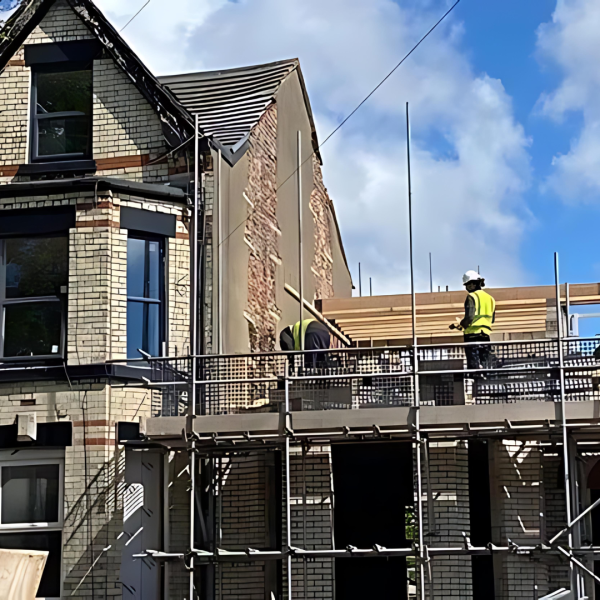 Construction work in progress showing roof extension with scaffolding and worker on site