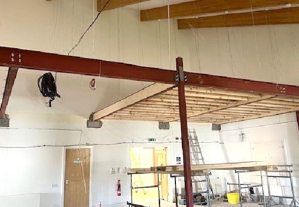 New Start Homes Liverpool office mezzanine floor structure installation showing steel beams and timber framework